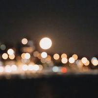 Bokeh of city traffic lights in red hues along an evening street