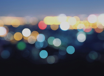 Abstract bokeh lighting on tall buildings with blue tint at twilight