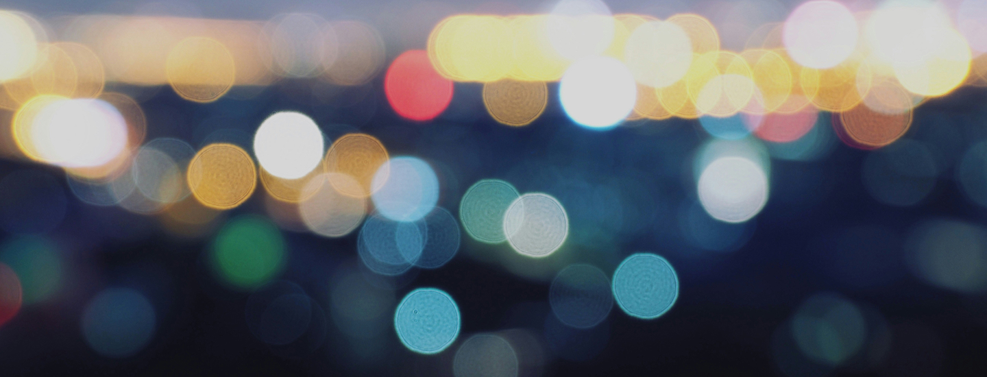 Abstract bokeh lighting on tall buildings with blue tint at twilight