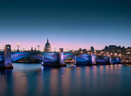 Long bridge illuminated with blue and purple lights in the dark